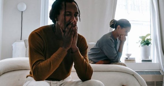 Couple sitting on bed after having argument leading to family separation.